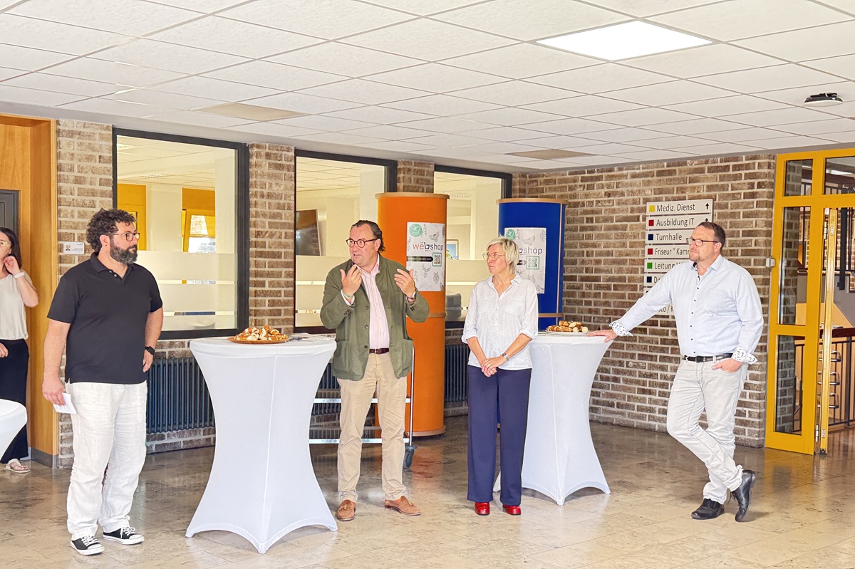 schulleiterin Fuchs eröffnet die Ausstellung am Stehtisch mit weiteren Gästen