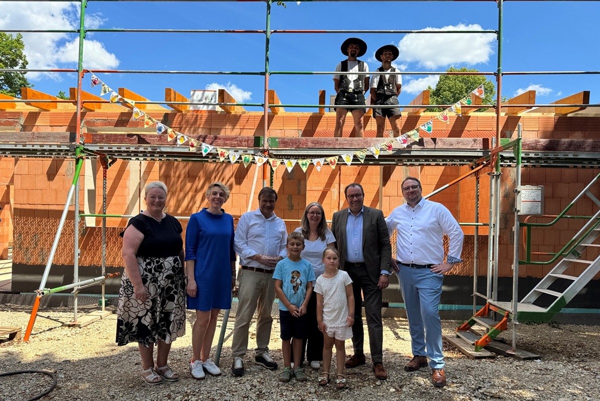 Gruppe von Menschen steht vor dem Rohbau Kinderhaus beim richtfest